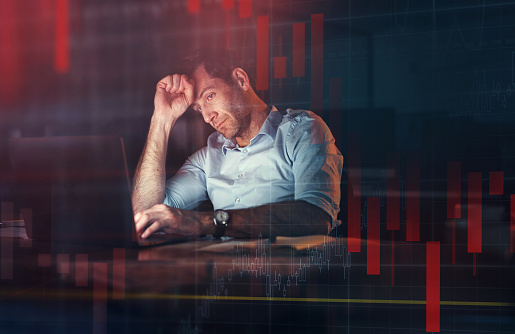 Stressed man, stock market and crypto on laptop in digital trading loss with red candlestick background. Online bitcoin trader of frustrated male in forex currency, investing and NFT with technology