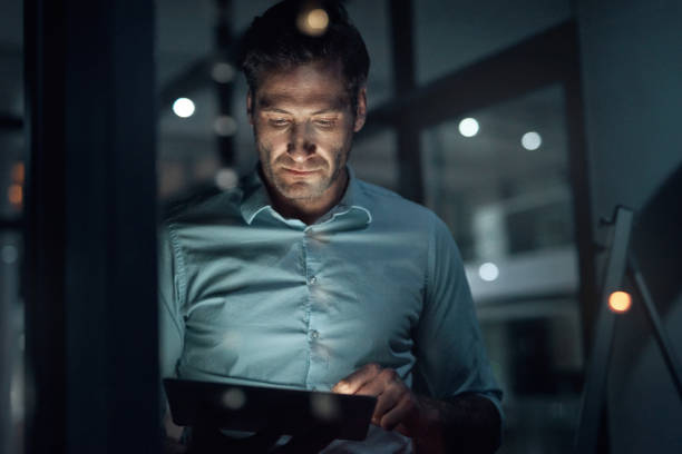 istock Serious man, tablet and communication while working late at night doing online research or digital marketing. Male entrepreneur using information technology for social media advertising or mobile app 1427840892