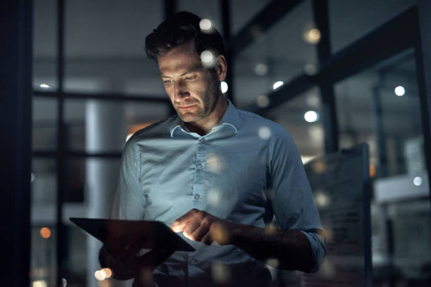 Business man, working and tablet of a employee doing digital, web and internet strategy planning. Corporate businessman and tech worker in the dark using technology to work on online and IT analytics stock photo