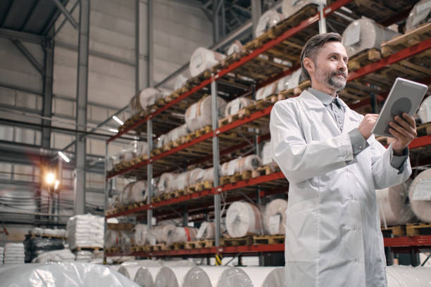 istock Man in white robe at factory shelves 1427844649