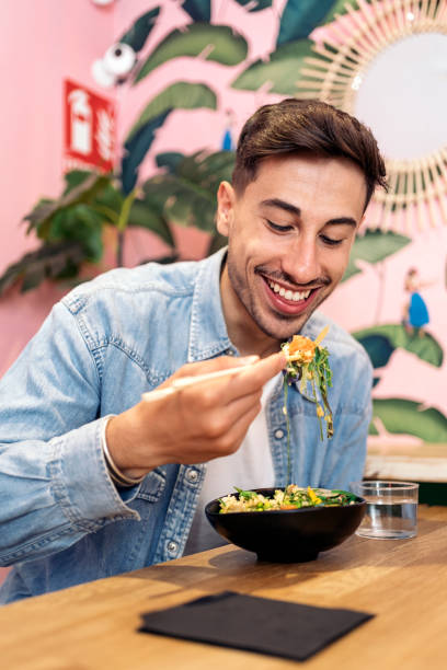 profiter du poke bowl - eating men food chopsticks photos et images de collection