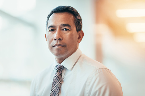 Portrait of Asian mature businessman serious in bright business office in businesswear