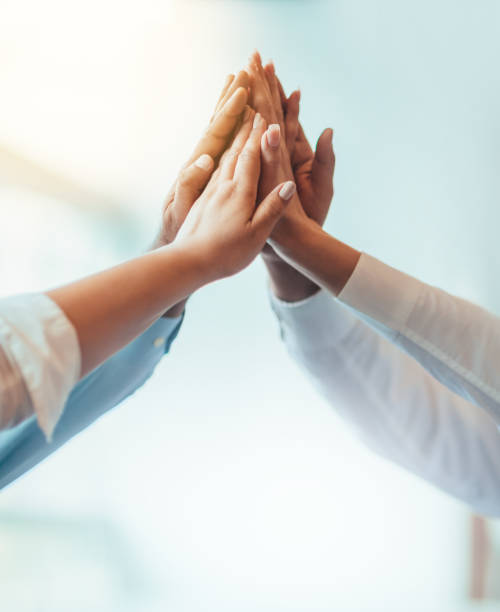 Multiracial group of students stacked hands high-five in agreement achievement success aspiration smiling in bright business office classroom Multiracial group of students stacked hands high-five in agreement achievement success aspiration smiling in bright business office classroom business handshake partnership human hand stock pictures, royalty-free photos & images