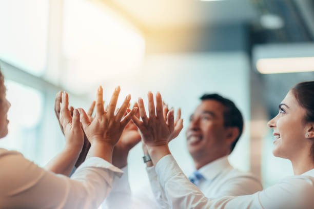 Multiracial group of business persons students clasping hands in stacked hands high-five lifting concept in team building success educational classroom office looking up with bright light grupo multirracial de personas de negocios estudiantes que se agarran las manos en manos apiladas concepto de levantamiento de cinco altos en el éxito de la construcción de equipos aula educativa oficina mirando hacia arriba con luz brillante