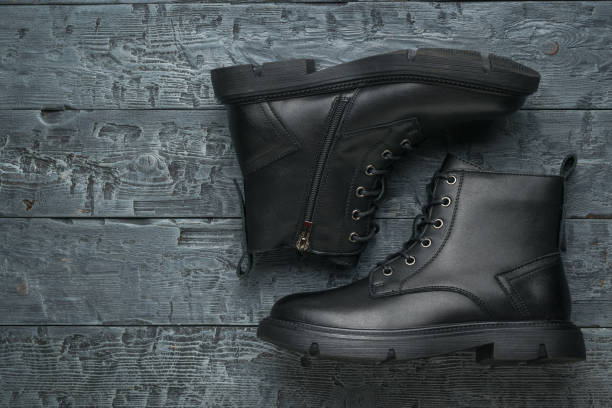istock Black leather boots on a black wooden table. 1427848409