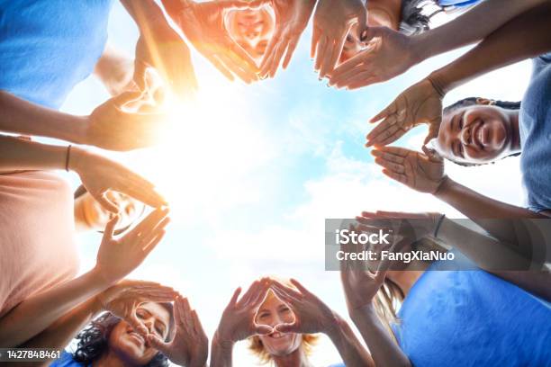 Multiracial Group Of Diverse People Stand In Circle As Community Volunteers To Show Support And Commitment To Teamwork Success Togetherness Making Hand Gesture In Concept Symbol Sign Of Heart Shape Outdoors With Sky Stock Photo - Download Image Now