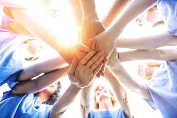 istock Multiracial group of men and women make stacked hands together in community support teamwork success togetherness as environmental social issues volunteers smiling with sky and sunlight 1427848609