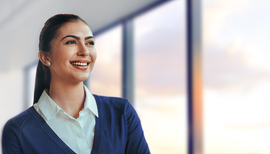 Portrait of Slavic woman student smiling positive emotion happiness looking away forward in aspiration success well-dressed in bright office with window sky