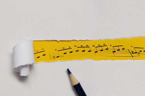 Music notes under torn white  paper.