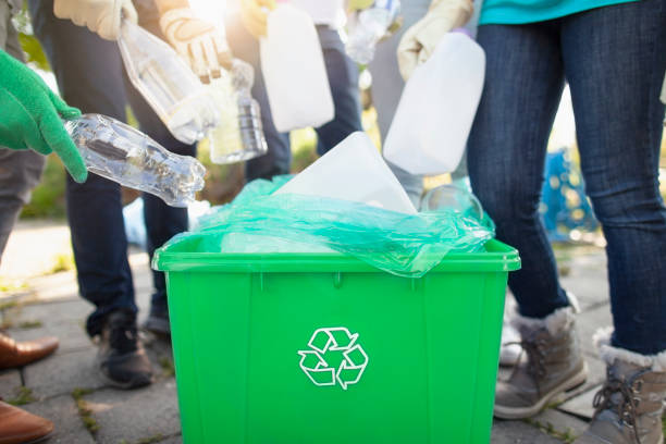 Group of volunteers with youth organization charity help cleanup recycle plastic bottles into recycle bin in local public park in residential neighborhood together stock photo