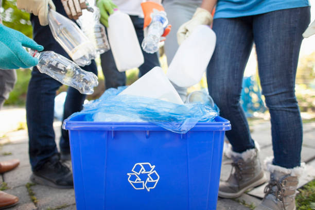 Group of volunteers with youth organization charity help cleanup recycle plastic bottles into recycle bin in local public park in residential neighborhood together stock photo