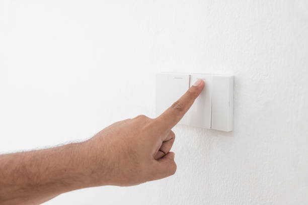 istock Close-up light switch of a male finger will turn on or off a light switch with white wall at home. white plastic mechanical switch mounted. Energy, energy, save electricity, copy space 1427861265
