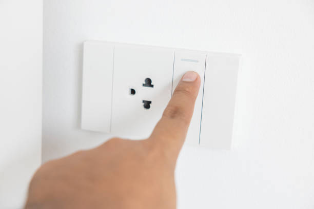 istock Close-up light switch of a male finger will turn on or off a light switch with white wall at home. white plastic mechanical switch mounted. Energy, energy, save electricity, copy space 1427861297