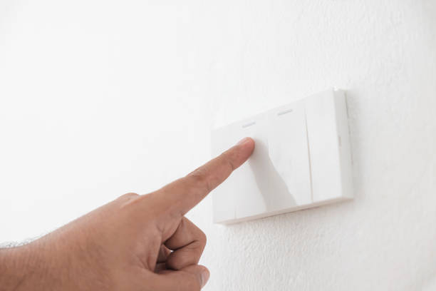 istock Close-up light switch of a male finger will turn on or off a light switch with white wall at home. white plastic mechanical switch mounted. Energy, energy, save electricity, copy space 1427862391