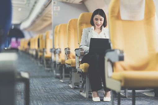 Asian Business woman working with laptop in the airplane before go to travel.
