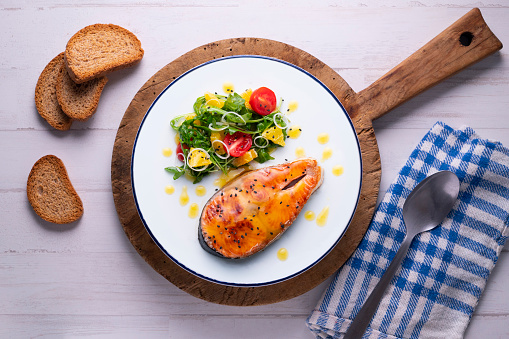 Grilled salmon with orange sauce and a salad. Typical Mediterranean coast dish.