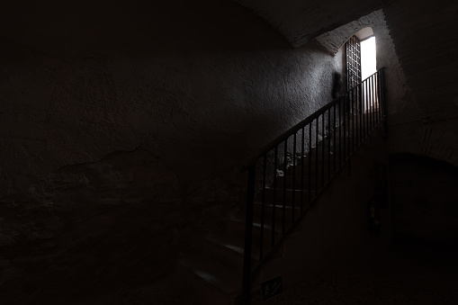 Light coming through the door.  Old wrought iron stairs.  Light at the end of the stairs.  Mysterious scene.