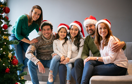 Happy Latin American family celebrating Christmas together at home and looking at the camera smiling - holidays concepts