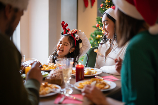 Latin American girl having Christmas dinner with her family and looking very happy - holiday season concepts
