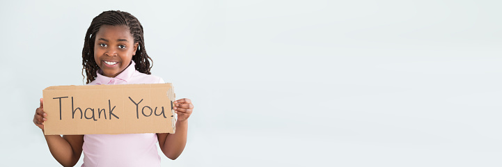 Close-up Of A Smiling African Girl Holding Thank You Sign Against White Background