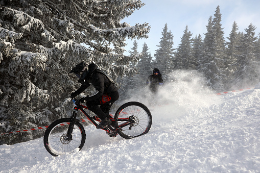 Sofia, Bulgaria - 22 January, 2022: Cyclist rides a bike downhill during an extreme snow riding mountain bicycle competition in Vitosha mountain.