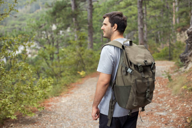 istock View from the back of young man with a hiking backpack walks along a path through a forest in the mountains. Active and healthy lifestyle concept 1427882357