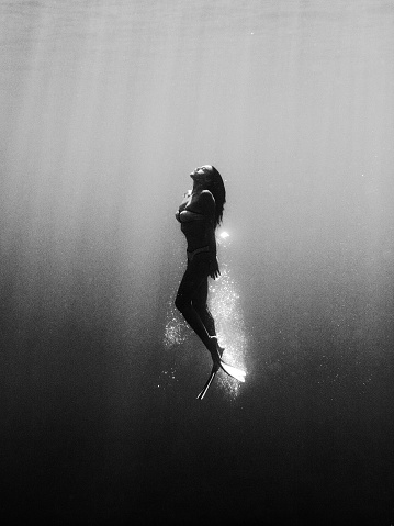 Underwater person in black and white with bubbles from black to clear