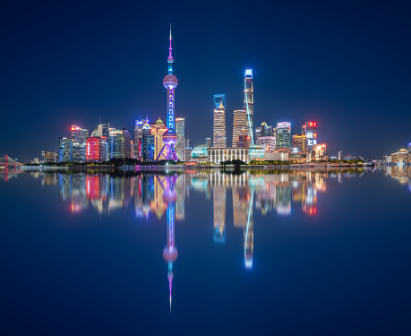 Shanghai skyline at dusk, showing the Huangpu river with passing cargo ships, and financial district in sunset