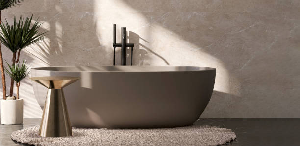 istock Gold brass side table by brown ceramic bathtub in luxury design bathroom and tropical tree with sunlight from window and leaf shadow on beige marble wall 1427889561