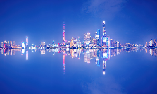 Shanghai skyline at dusk, showing the Huangpu river with passing cargo ships, and financial district in sunset