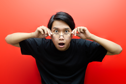 Portrait of young man with shocked facial expression isolated over red background