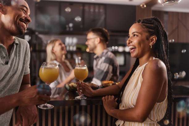 szczęśliwa czarna para rozmawiająca podczas spotkania towarzyskiego w domu. - juice drinking women drink zdjęcia i obrazy z banku zdjęć