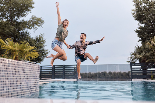 A little boy and little girl jumping off the dock into a beautiful mountain lake. Having fun on a summer vacation