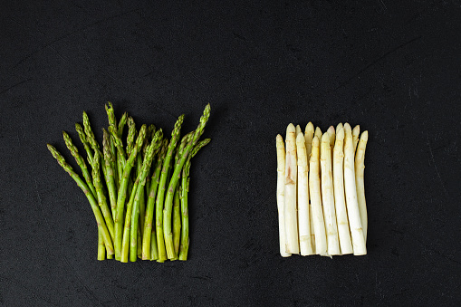 Fresh white and green asparagus on black slate background. Top view copy space.
