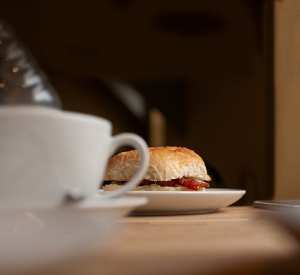 Fresh bacon roll/butty/sandwich sat alongside a morning cup of coffee with copy space above