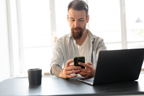 istock Handsome young bearded man spending time at home with phone in hands. 1427909927