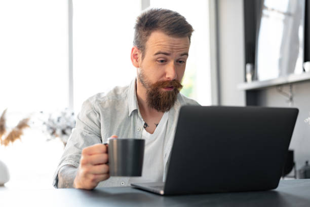 istock Stylish bearded man working on laptop from home sitting at the table 1427909983