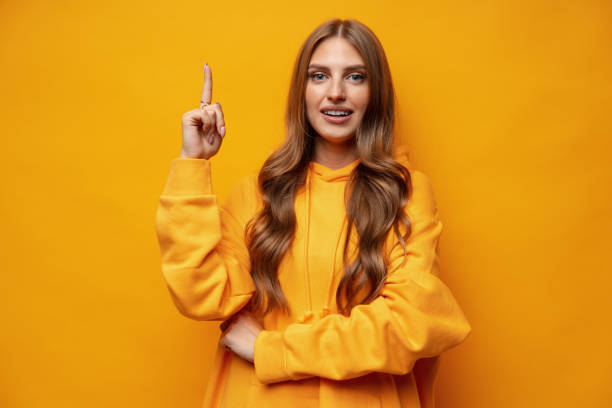 istock Young pretty woman pointing at copy space in studio 1427910219