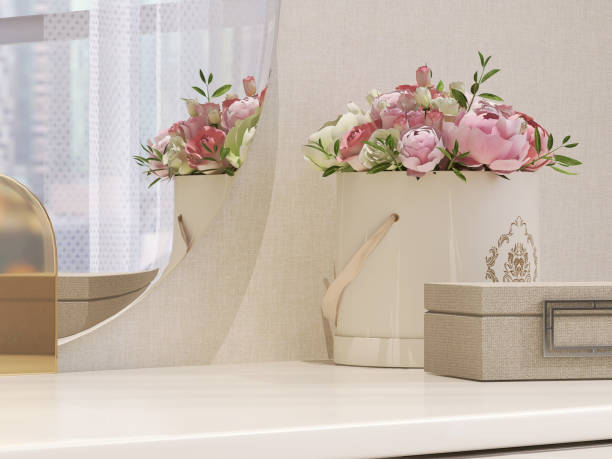 美しく豪華な木製のベージュのドレッシングテーブル、バラの花のバケツとベッドルームのフレームレス丸い鏡