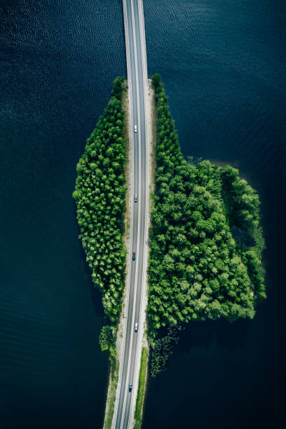 Aerial view of road through blue lakes or sea with green woods in Finland. stock photo