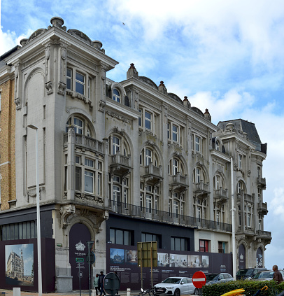 Facade of the Ritz along Piccadilly during the day. People can be seen outside the building. Car parked in front of the hotel. British flag