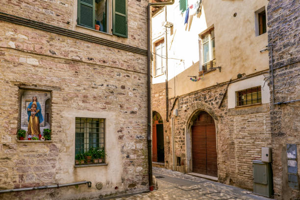 eine steinerne gasse mit einem gemälde der jungfrau maria im herzen der mittelalterlichen stadt foligno - corner stone wall brick stock-fotos und bilder