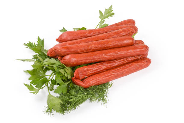istock Long thin smoked sausages on greens on white background 1427919410