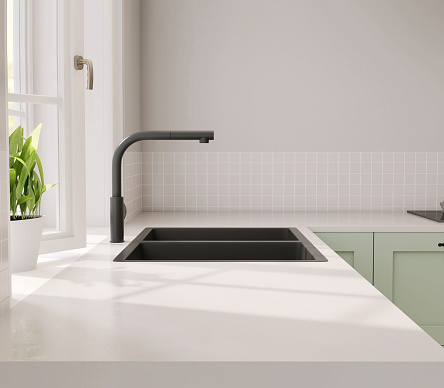 Minimal and contemporary green kitchen counter with white laminated plastic top and black quartz sink with sunlight from window on wall for product display