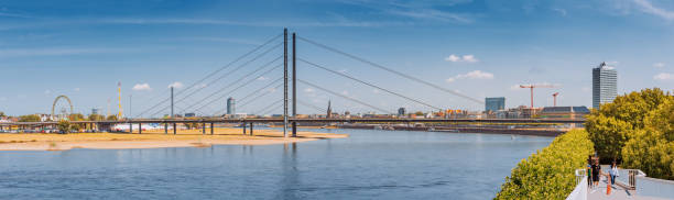 Panoramic cityscape view of Suspension automobile bridge Rheinkniebrucke over the Rhine River 23 July 2022, Dusseldorf, Germany: Panoramic cityscape view of Suspension automobile bridge Rheinkniebrucke over the Rhine River panoramic riverbank architecture construction site stock pictures, royalty-free photos & images