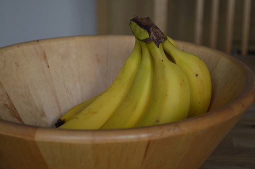 A bunch of perfectly ripe bananas in a bamboo wood fruit bowl