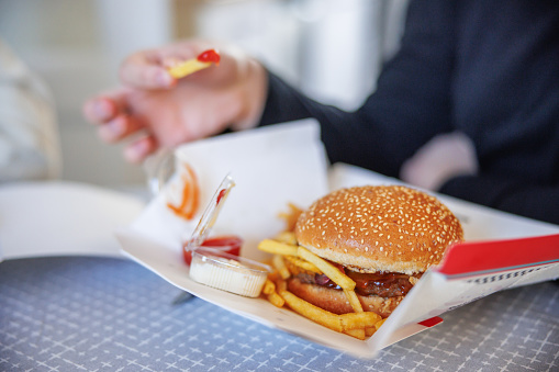 Eating take out at home, burgers and fries with dipping sauces in cardboard box