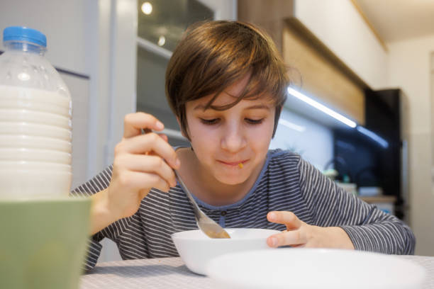 istock Preadolescent boy eating cereal with milk at the table at home 1427925685