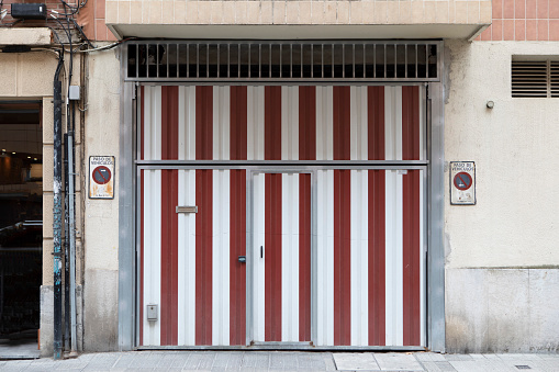 Red and white striped garage doors leading directly onto the street in Bilbao, Spain