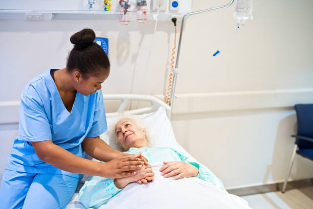 nurse consoling senior patient in hospital - hospital patient bed nurse imagens e fotografias de stock